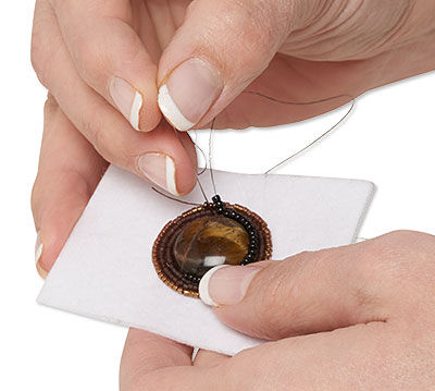 Seed beads being embroidered around a cabochon